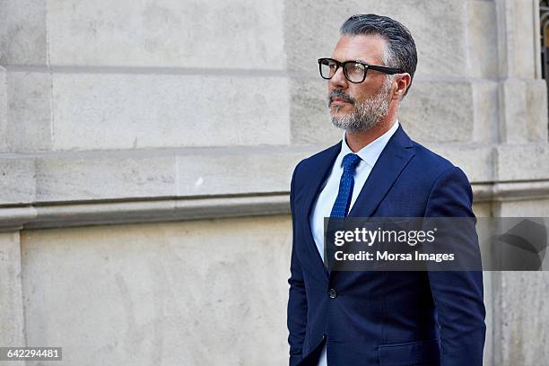 thoughtful businessman against building - beard glasses stock pictures, royalty-free photos & images