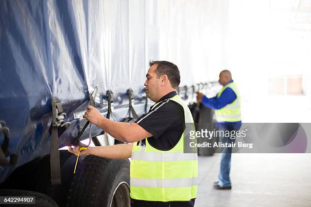 workers loading a lorry at a large warehouse - dekzeil stockfoto's en -beelden