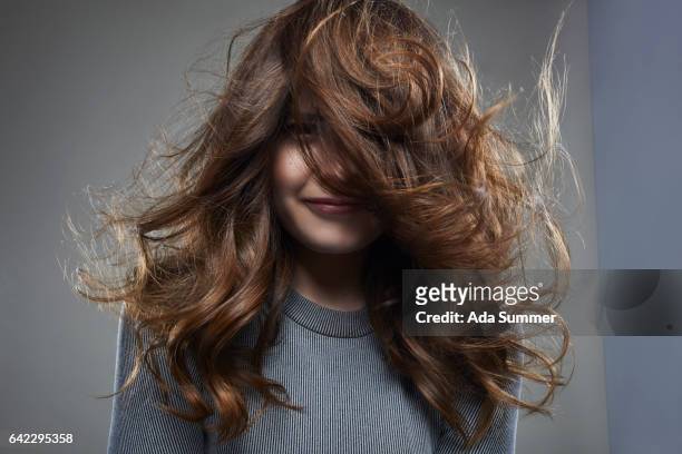 smiling young woman with long messy brown hair - teased hair stock pictures, royalty-free photos & images