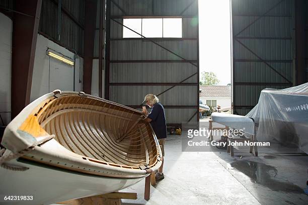 mature male handcrafting wooden boat - scheepswerf stockfoto's en -beelden