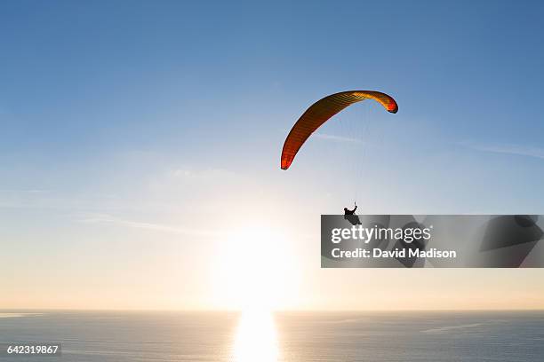 paraglider sailing over ocean at sunset - parapente fotografías e imágenes de stock