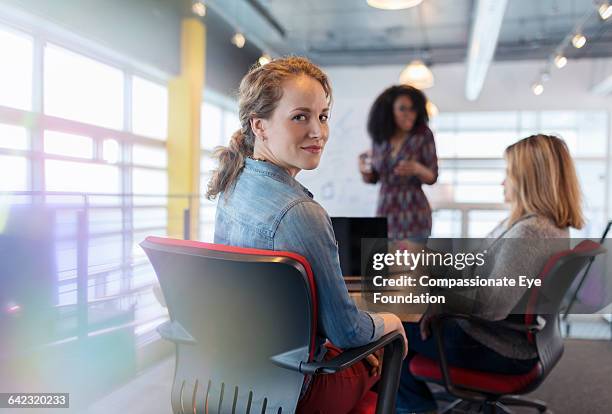 businesswoman using laptop in meeting - portrait looking over shoulder stock pictures, royalty-free photos & images