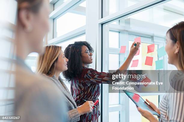 businesswomen discussing project in office - postit stockfoto's en -beelden