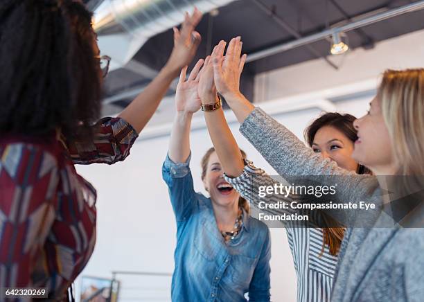 businesswomen cheering in office - high five people stock pictures, royalty-free photos & images