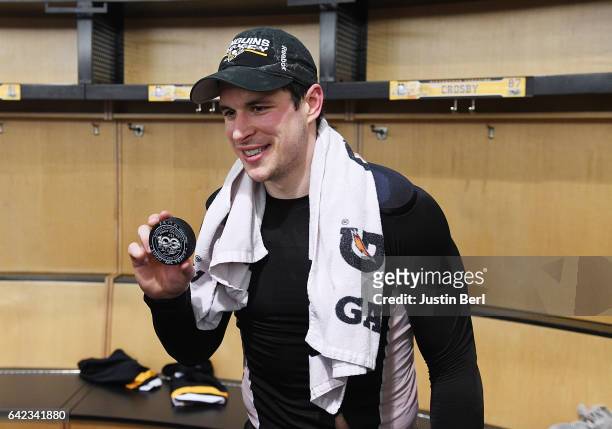 Sidney Crosby of the Pittsburgh Penguins poses with the puck he scored his 1000th career point with after the Pittsburgh Penguins 4-3 win over the...