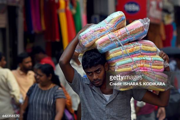 Sri Lankan man transports cloth for sale at a market in Colombo on February 17, 2017. / AFP / Ishara S. KODIKARA