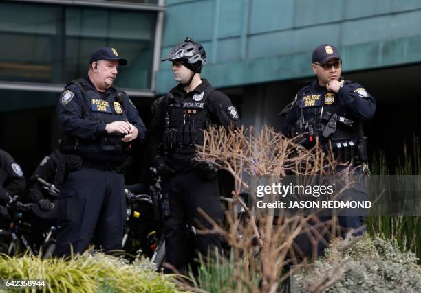 Department of Homeland Security officers watch as protesters gather outside US District Court, in Seattle Washington on February 17 before a hearing...
