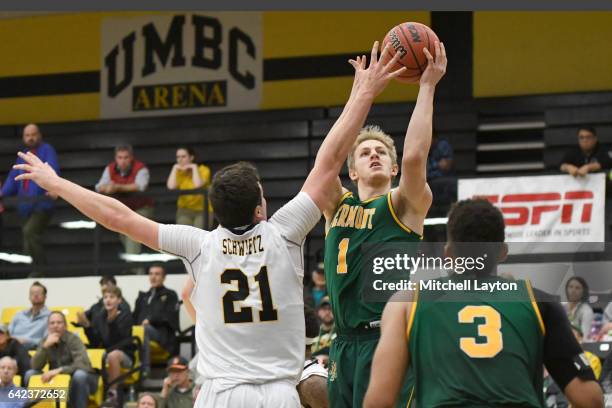 Josh Hearlihy of the Vermont Catamounts takes a shot over Sam Schwietz of the UMBC Retrievers during a college basketball game at the RAC Arena on...