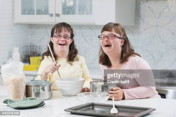 two sisters with down syndrome, in the kitchen - down syndrome cooking stock pictures, royalty-free photos & images