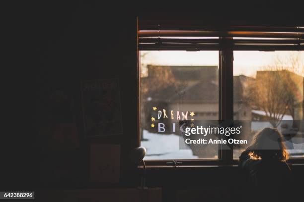 little girl looking out a bedroom window - curls girl silhouette ストックフォトと画像