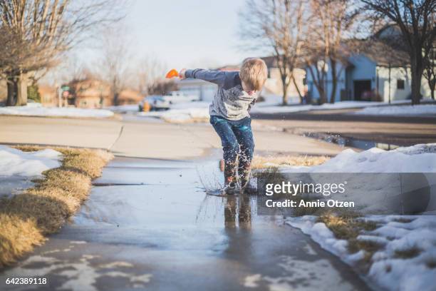 boy jumping - snow melting on sidewalk stock pictures, royalty-free photos & images