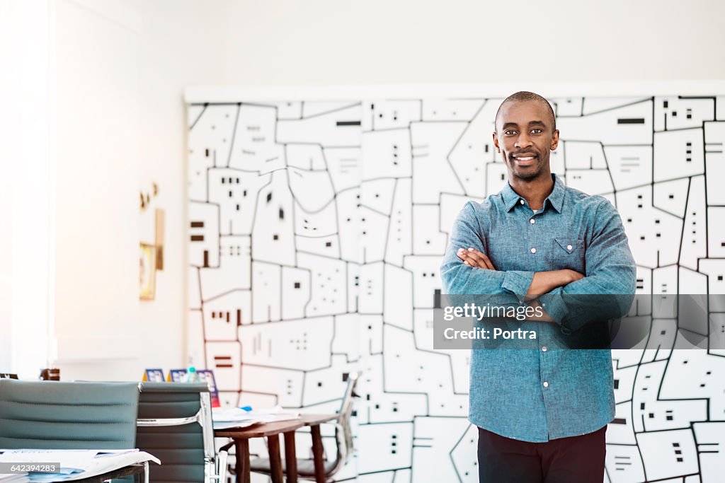 Smiling architect with arms crossed in office