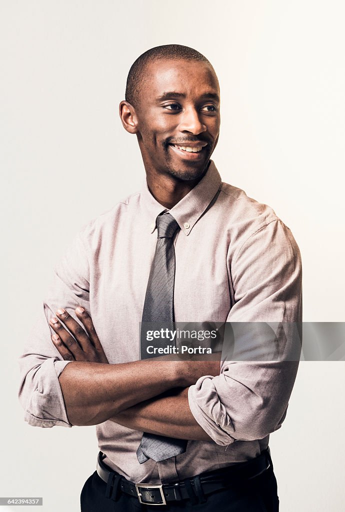 Thoughtful smiling businessman with arms crossed