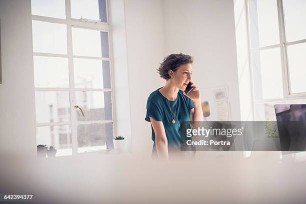 businesswoman talking on mobile in creative office - focus on background stock pictures, royalty-free photos & images