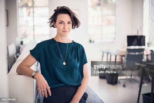smiling businesswoman in creative office - informeel zakelijk stockfoto's en -beelden