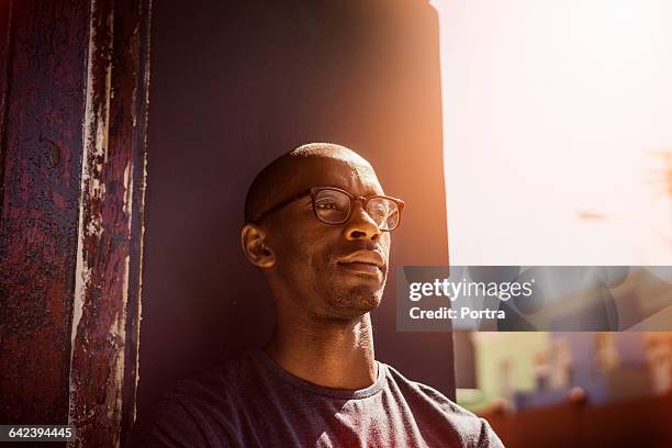 thoughtful man leaning on wall in city - focus noir photos et images de collection