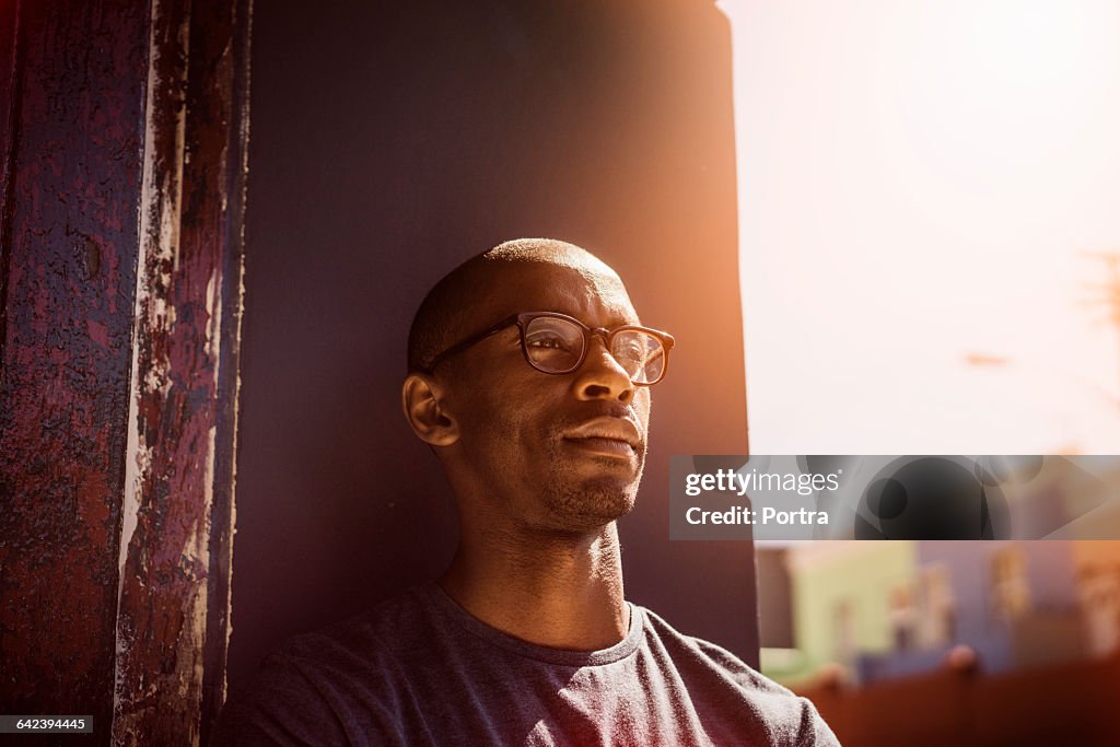 Thoughtful man leaning on wall in city