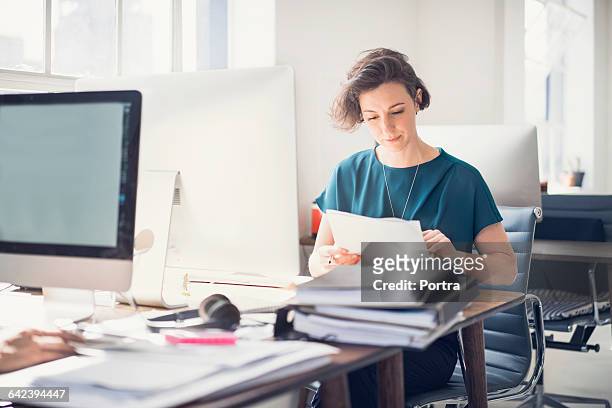 businesswoman reviewing paperwork in office - paperwork stock pictures, royalty-free photos & images