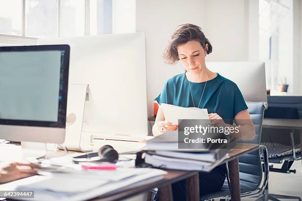 businesswoman reviewing paperwork in office - document review stock pictures, royalty-free photos & images