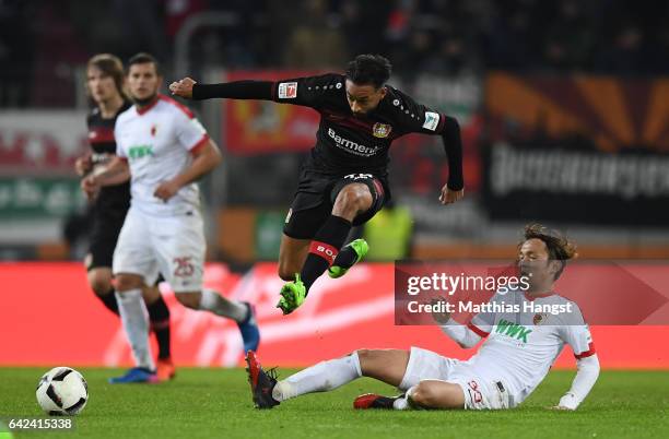 Karim Bellarabi of Leverkusen is challenged by Takashi Usami of Augsburg during the Bundesliga match between FC Augsburg and Bayer 04 Leverkusen at...