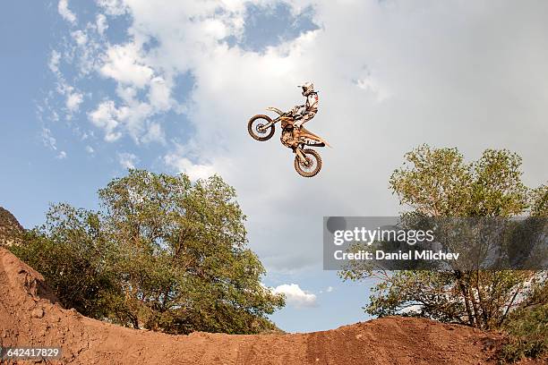 man jumping his dirt bike over a big jump. - motorcycle stunt stock pictures, royalty-free photos & images