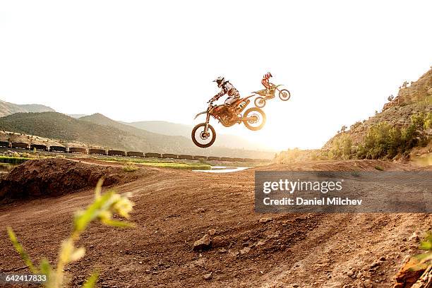 two dirt bike riders jumping during sunset. - motocross ストックフォトと画像