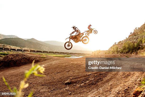 two dirt bike riders jumping during sunset. - motocross stockfoto's en -beelden