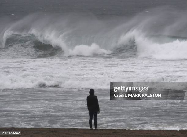 People watch the large waves at El Porto beach as the strongest storm in six years slams Los Angeles, California, on February 17, 2017. / AFP / Mark...