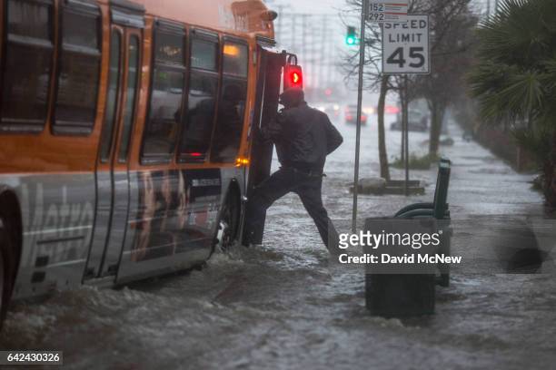 Man boards a bus on a flooded street as a powerful storm moves across Southern California on February 17, 2017 near Sun Valley, California. After...