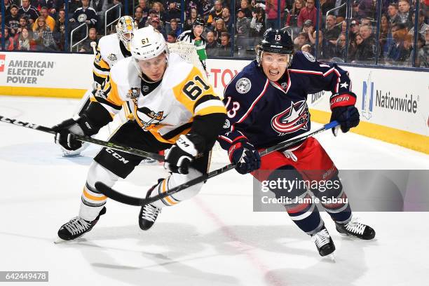 Steve Oleksy of the Pittsburgh Penguins and Cam Atkinson of the Columbus Blue Jackets battle for position as they skate after a loose puck during the...