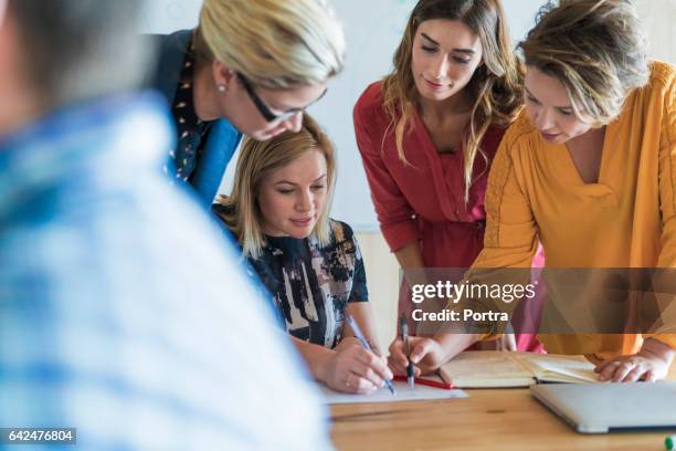 geschäftsfrauen diskutieren über projekt im büro - fokus-auf-den-hintergrund stock-fotos und bilder