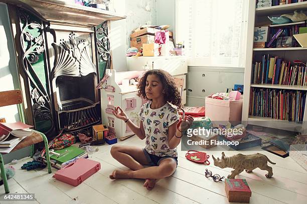 girl meditating in bedroom - messy playroom stock-fotos und bilder