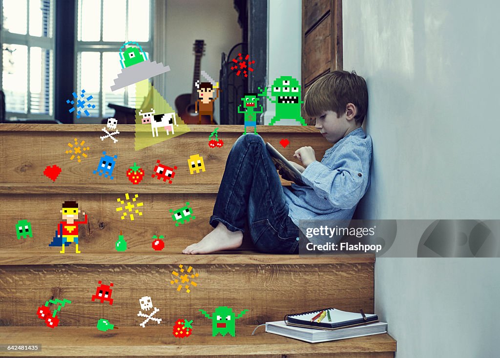 Boy playing on digital tablet with game symbols