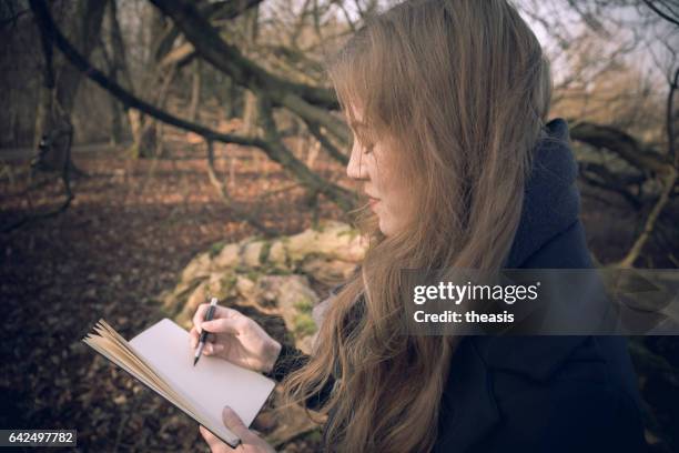 attractive young woman writing in her journal - theasis stock pictures, royalty-free photos & images