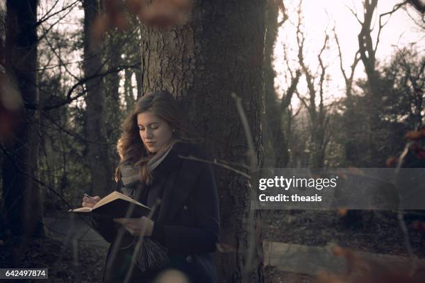 attractive young woman writing in her journal - theasis stock pictures, royalty-free photos & images