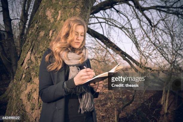 atractiva mujer joven escribiendo en su diario - theasis fotografías e imágenes de stock