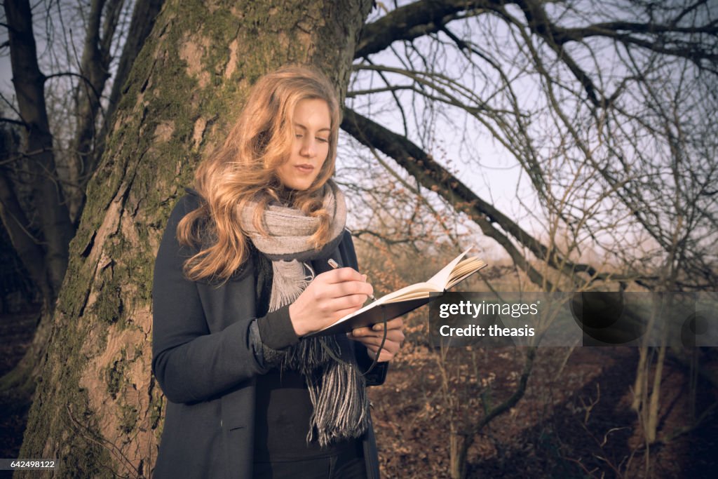 Attractive young woman writing in her journal