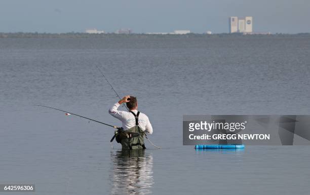 The Vehicle Assembly Building at Kennedy Space Center looms in the distance as a fisherman gets an early start near Port Canaveral, Florida on...