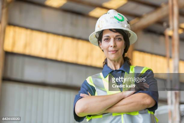hispanische arbeitnehmerin mit bauarbeiterhelm und sicherheit weste - hispanic construction worker stock-fotos und bilder