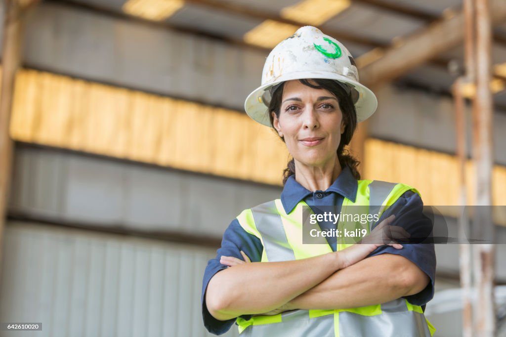 Hispanic female worker wearing hardhat and safety vest