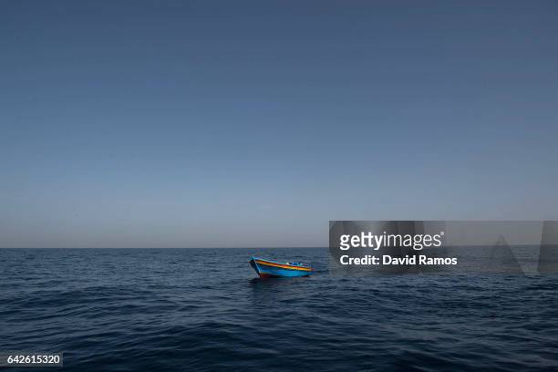 An empty wooden boat is left behind after migrants and refugees were assisted by members of the Spanish NGO Proactiva Open Arms as they crowd it...