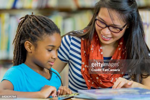 teacher reading with a student - teacher stock pictures, royalty-free photos & images