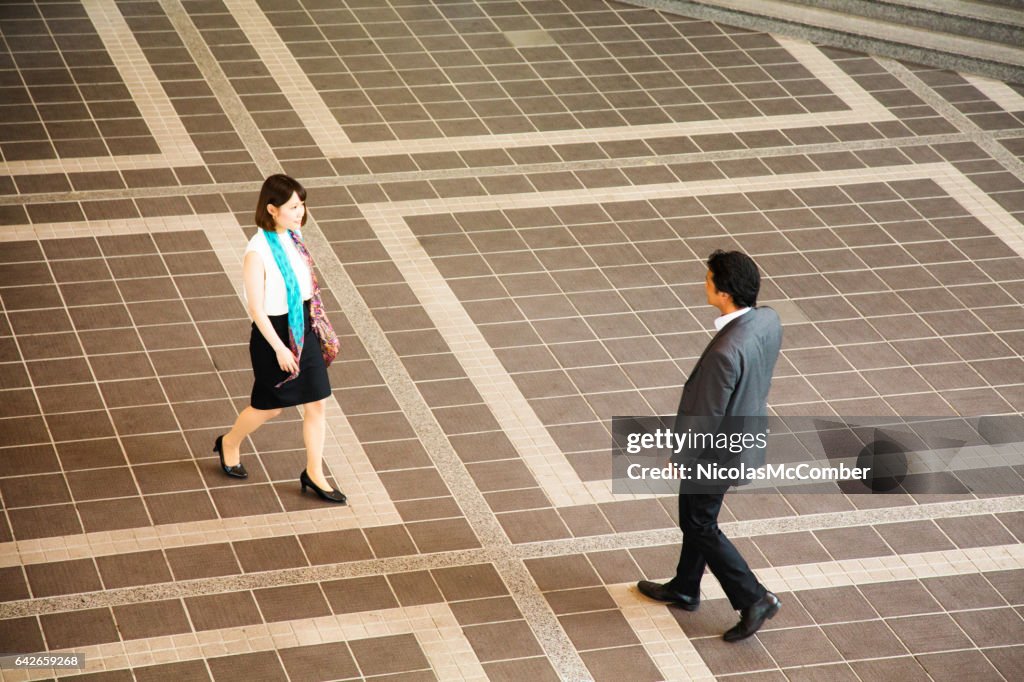 Verlegen Japanse zakenvrouw naderende collega