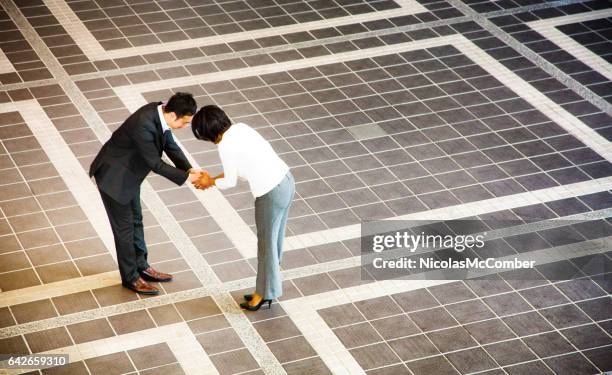 japanse zakenman buigen als hij handdrukken vrouwelijke collega - humility stockfoto's en -beelden