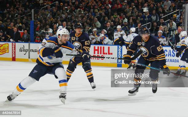 Kenny Agostino of the St. Louis Blues fires a backhand shot while being defended by Tyler Ennis and Marcus Foligno of the Buffalo Sabres during an...