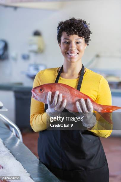 mixed race woman working in fish market - fishmonger stock pictures, royalty-free photos & images