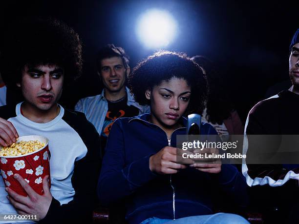 girl texting in movie theater - kinosaal stock-fotos und bilder