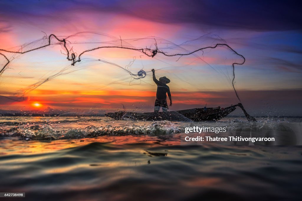 Silhouette Fisherman of traditional fishermen throwing net fishing at sunrise time