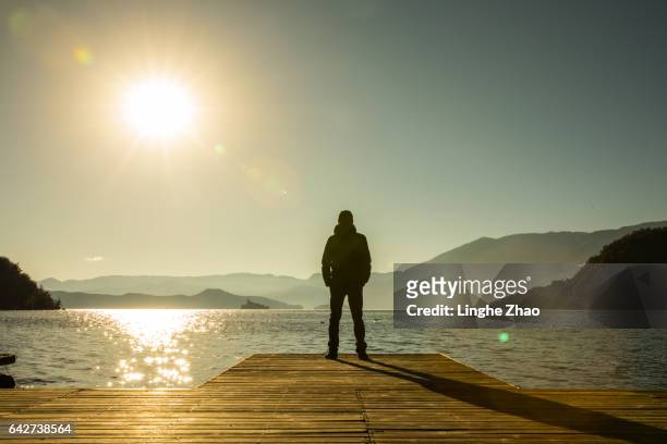 man standing at edge of pier by lake - pier 1 stock pictures, royalty-free photos & images