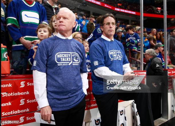Assistant coach Doug Jarvis and assistant coach Doug Lidster of the Vancouver Canucks wear Hockey Talks t-shirts on the bench before their NHL game...